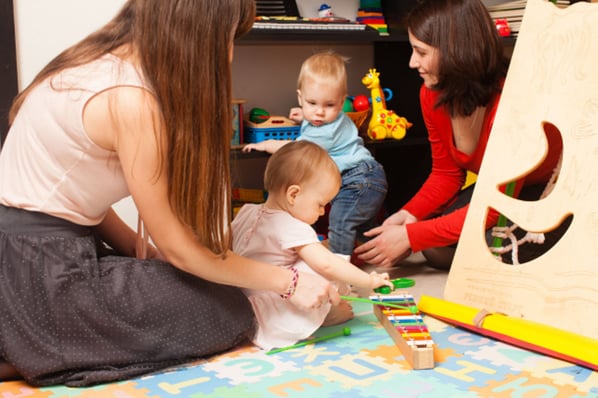Two women playing with babies at daycare center.