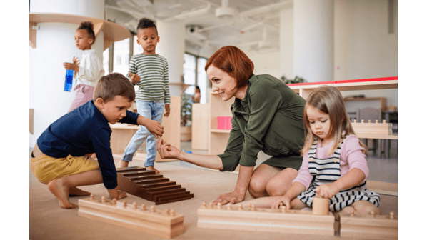 teacher-with-children-sitting-on-floor-montessori-min